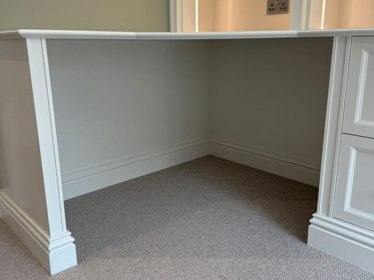 White corner desk with a spacious underside, featuring traditional moulding details.