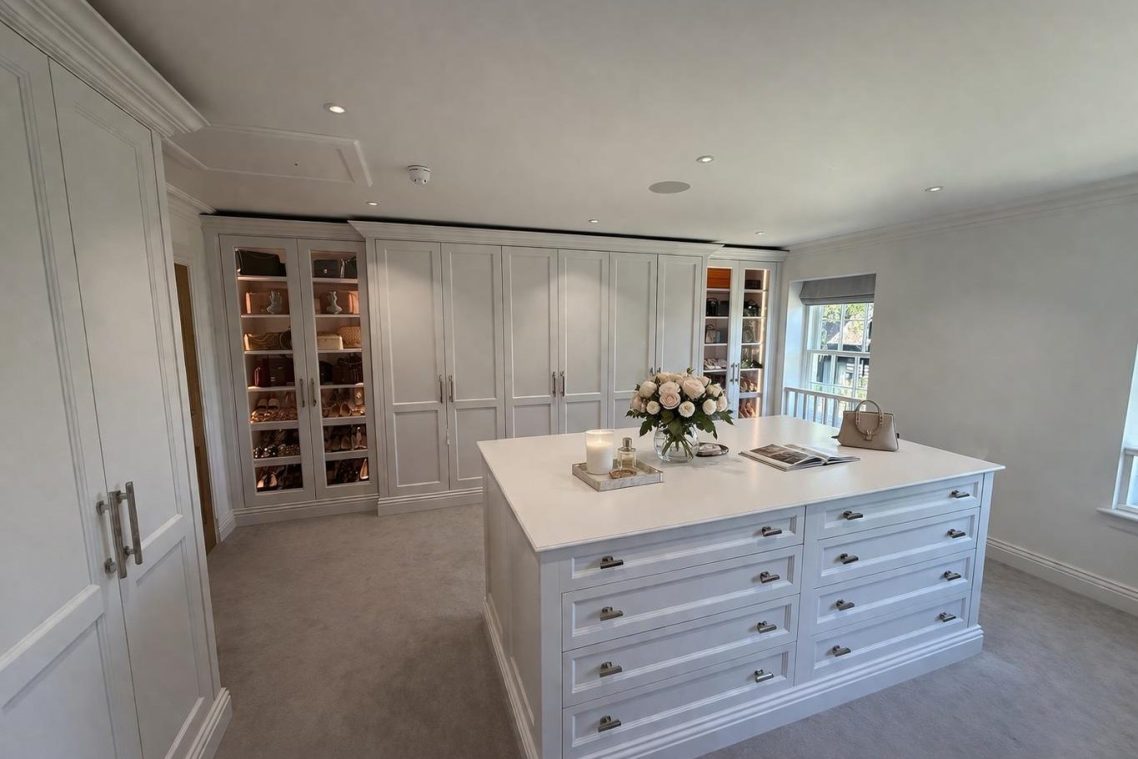 Spacious, elegant dressing room with a central white island and shelves neatly arranged.