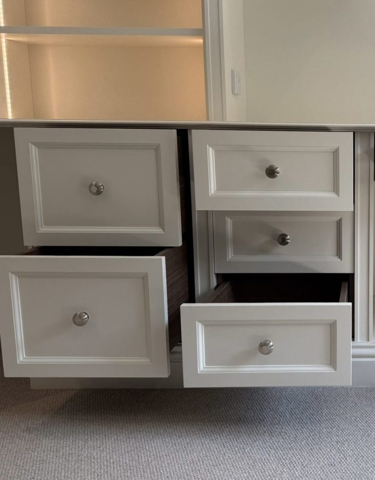 A set of white drawers with silver knobs, some open and some closed.