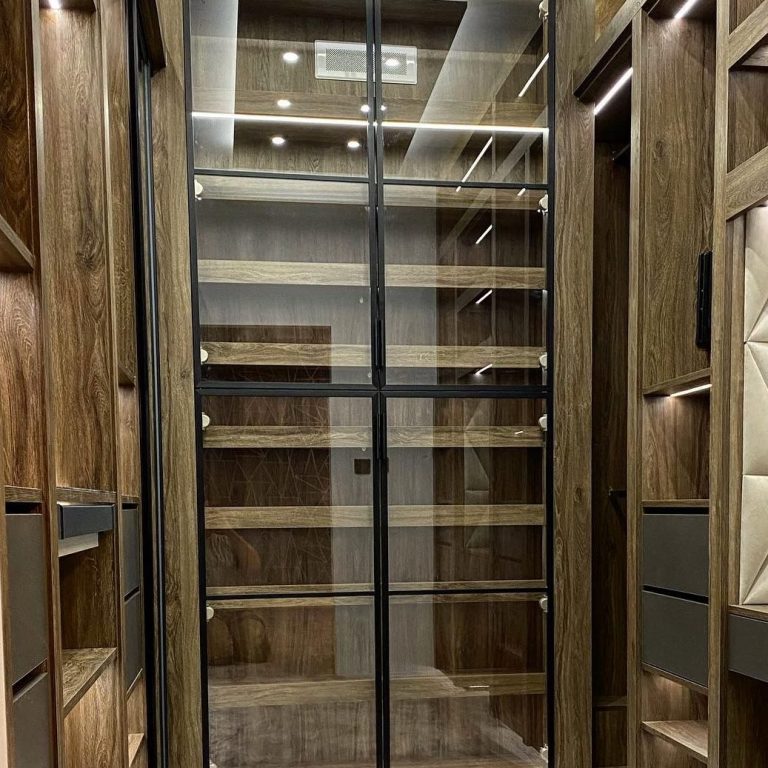 A modern wooden pantry with glass doors and empty shelving.