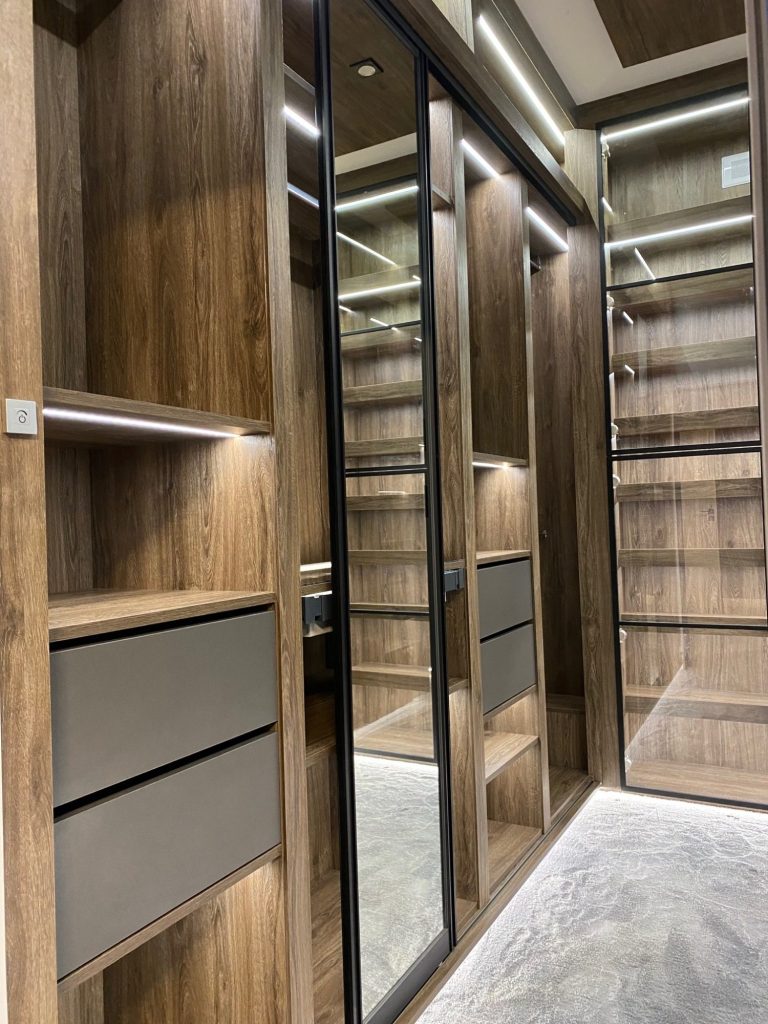 Modern closet with wooden shelves, mirrors, and integrated lighting.