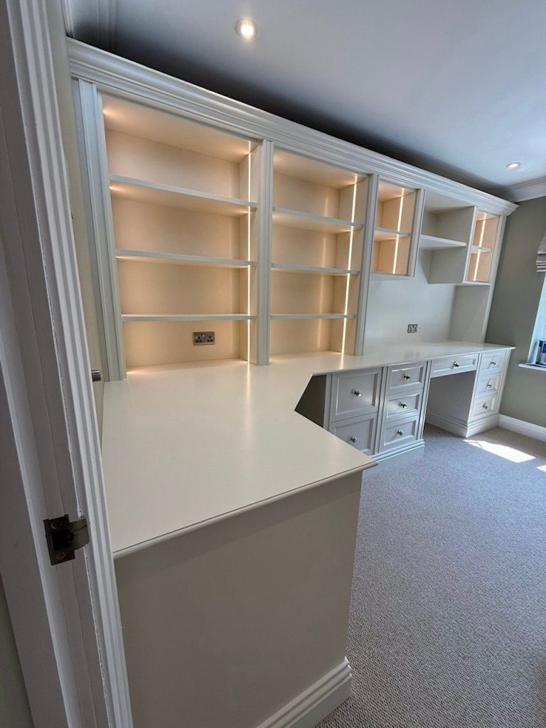 Modern study area with built-in shelves and a desk, featuring warm lighting.