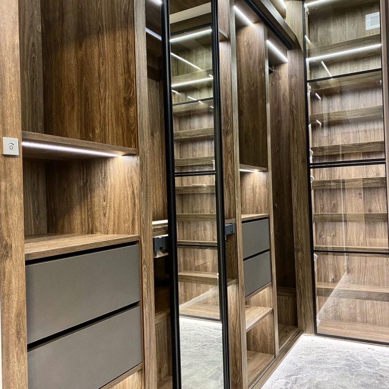Modern wooden wardrobe interior with shelves, drawers, and mirrors.
